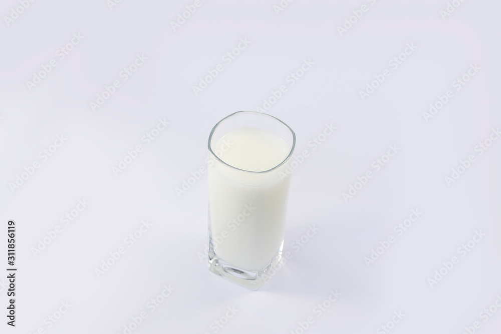 A cup of soy milk stands alone on a pale yellow background. A cup of soy milk stands alone on a pale yellow background.