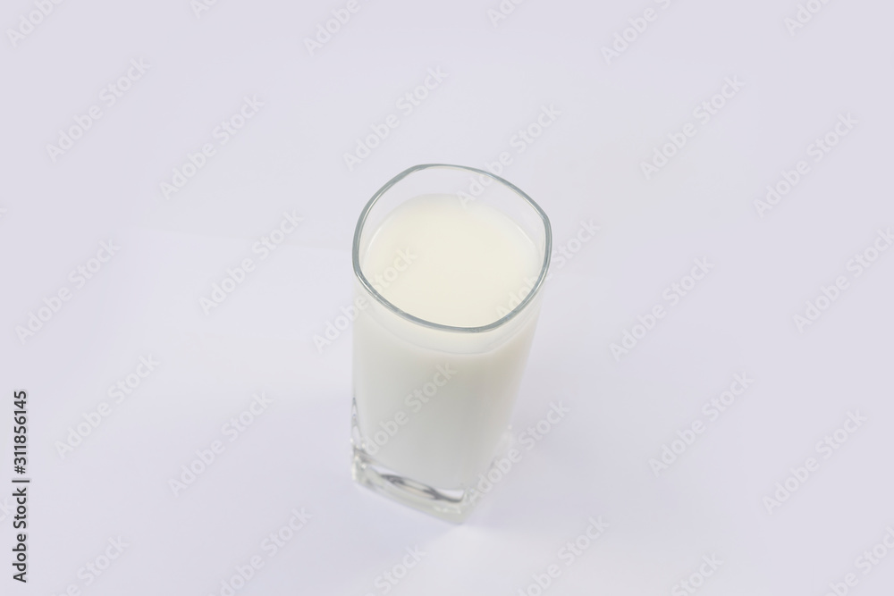 A cup of soy milk stands alone on a pale yellow background. A cup of soy milk stands alone on a pale yellow background.