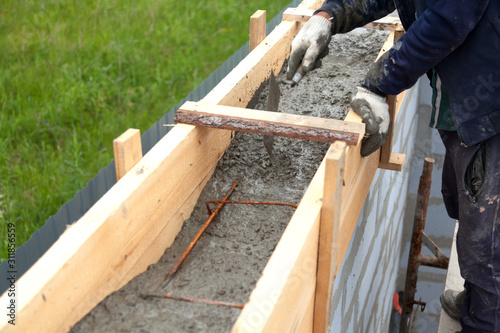 Worker levels concrete in formwork using a trowel photo
