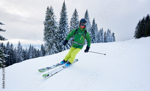 Skier man backcountry skiing on ski slope during vacation time. Recreational natural facilities. Concept of free risky sportive outdoors lifestyle. Monochrome winter mountains view on background. #311856768