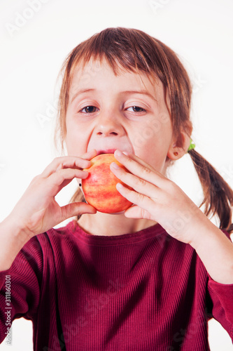 Close up portrait of a serious child girl with apple as symbol of diet and healthy food. Vertical image.