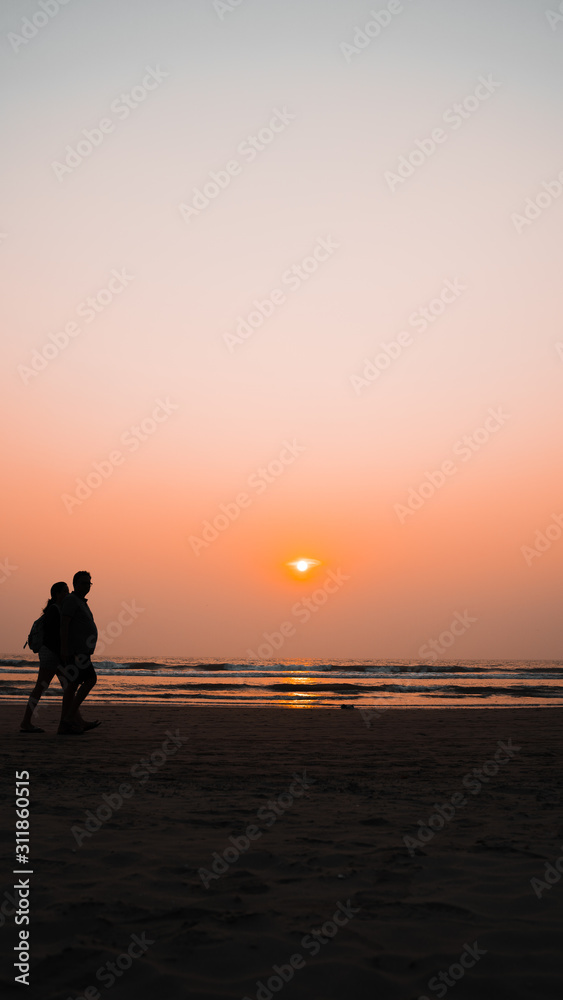 Sunset over sea and beach. Cloudless sundown sky over waving sea and sandy beach in evening on resort