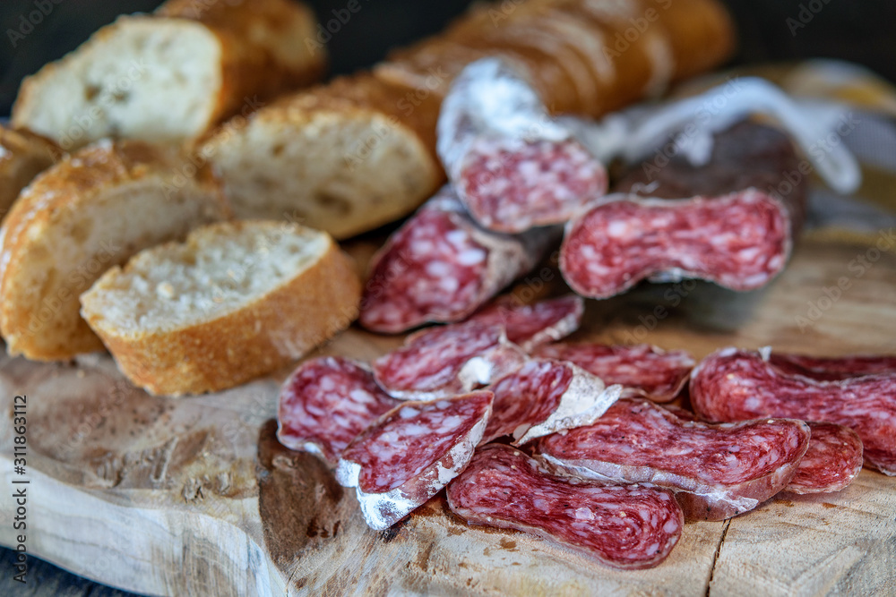 Slices of delicious spanish sausage fuet and white bread on the wooden natural kitchen board closeup. Healthy food concept. Slices of delicious spanish sausage fuet and white bread on the wooden natural kitchen board closeup. Healthy food concept.