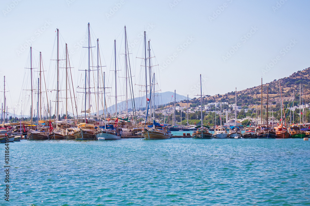 Beautiful luxury white yachts, ships and sailing boats moored at Bodrum marina on shores of blue Aegean sea near famous Bodrum Castle, Mugla, Turkey. Colorful seascape, travel concept. Turkish resort 
