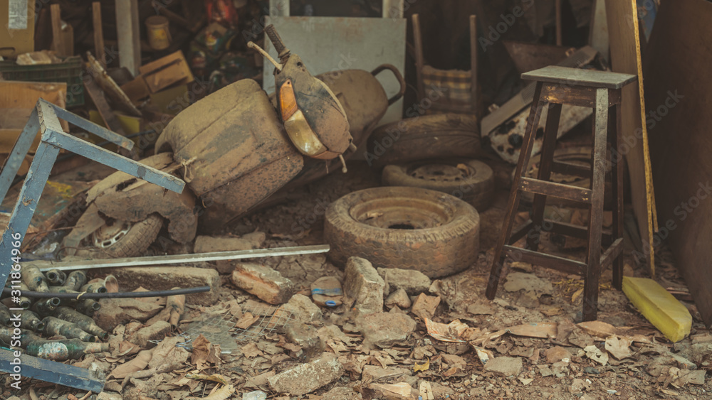 An old scooter is lying in a dump. A lot of old junk in the dust and dirt. An old scooter is lying in a dump. A lot of old junk in the dust and dirt.