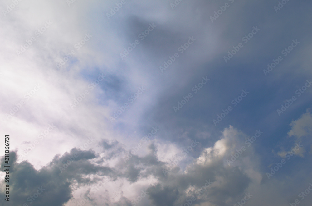 Blue sky and fluffy clouds. Beautiful cloudscape background. Sunlight on the clouds. Blue gradient.