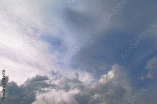 Blue sky and fluffy clouds. Beautiful cloudscape background. Sunlight on the clouds. Blue gradient.