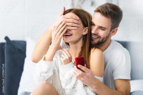 smiling man doing marriage proposal and obscuring face of woman