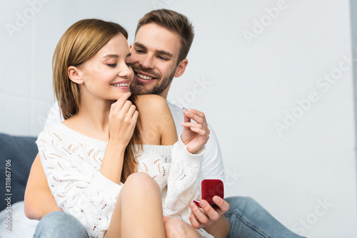 handsome man doing marriage proposal to smiling and attractive woman