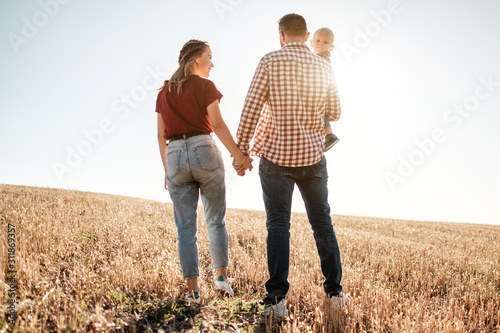 Happy Young Family Mom and Dad with Their Little Son Enjoying Summer Weekend Picnic Outside the City in the Field at Sunny Day Sunset  Vacation Time Concept