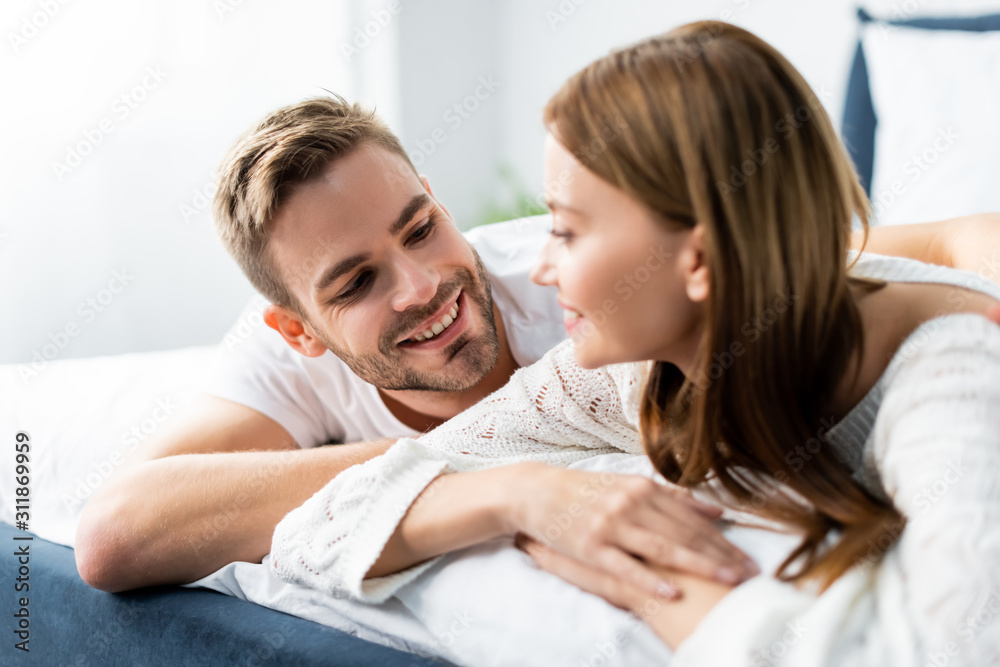 handsome man looking at attractive and smiling woman in apartment handsome man looking at attractive and smiling woman in apartment