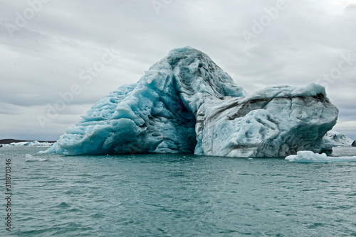 Icebergs with volcanic ash layers floating on water in a glacier lagoon