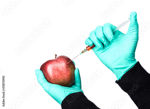 Human being injected chemicals into red apple, pesticides and fertilizers and chemicals with a syringe. photo