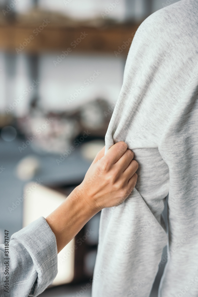 cropped view of woman touching sweatshirt of man