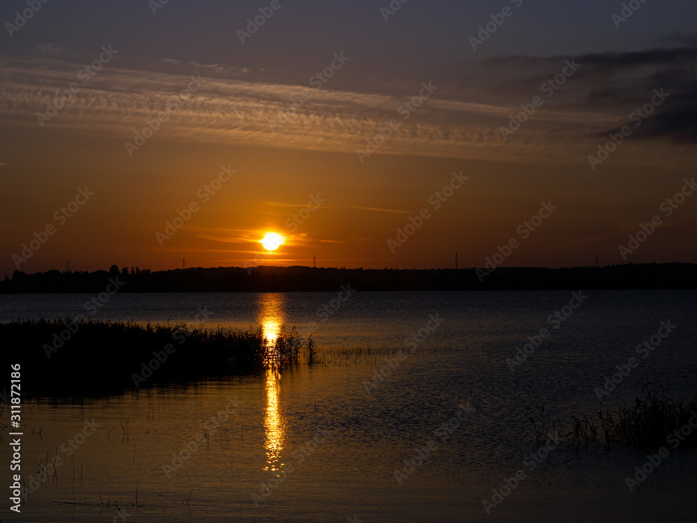 landscape with sunset in the background, lake sand and grass in the foreground