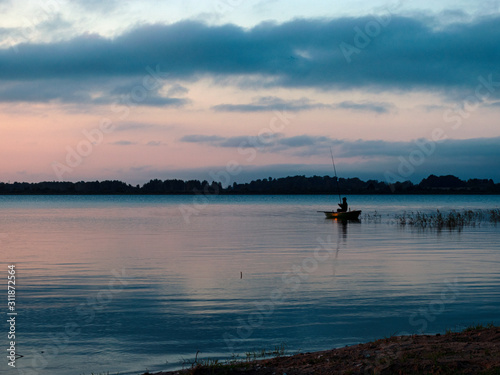 evening light on the lake, fisherman in boat, dusk