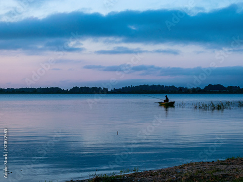 evening light on the lake, fisherman in boat, dusk