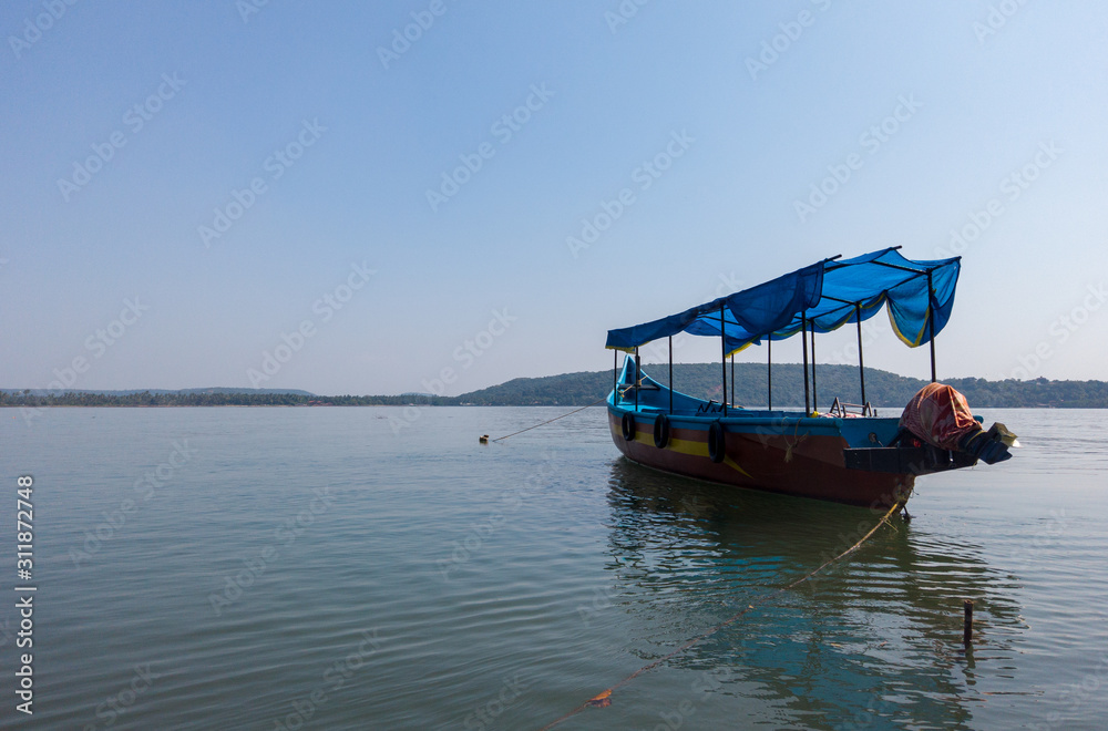 Colorful tourist boat in sea. Bright tourist boat with person on board floating on calm sea water against cloudless blue sky on sunny day on resort