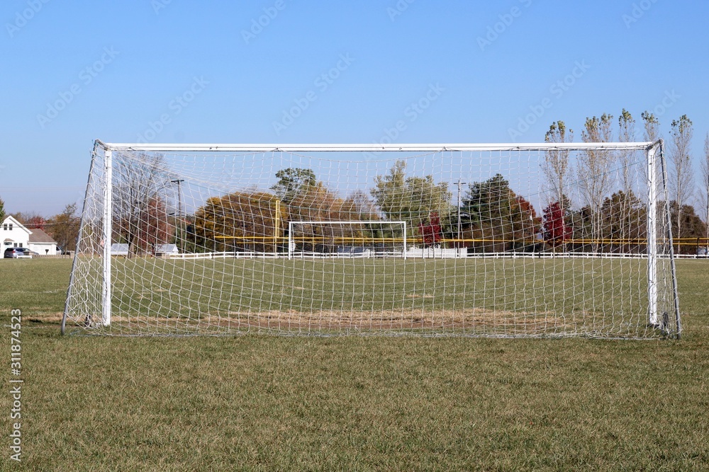 Fototapeta premium A view behind the white soccer goal net in the field.