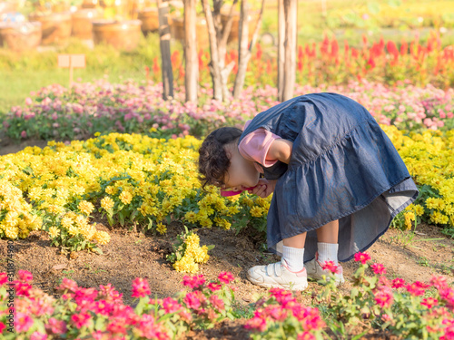 The girl standing in the field, using a magnifying glass to look at the flowers