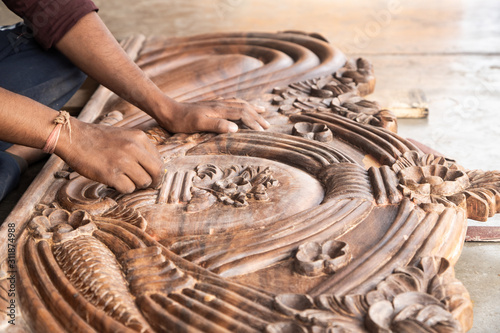 beautiful carved woodwork in an Indian street workshop. The hands of an Indian carpenter polishing the carved wooden headboard.