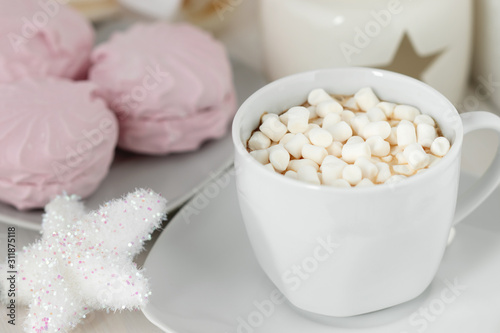 White сup of coffee with marshmallows on the background of sweets and Christmas decor