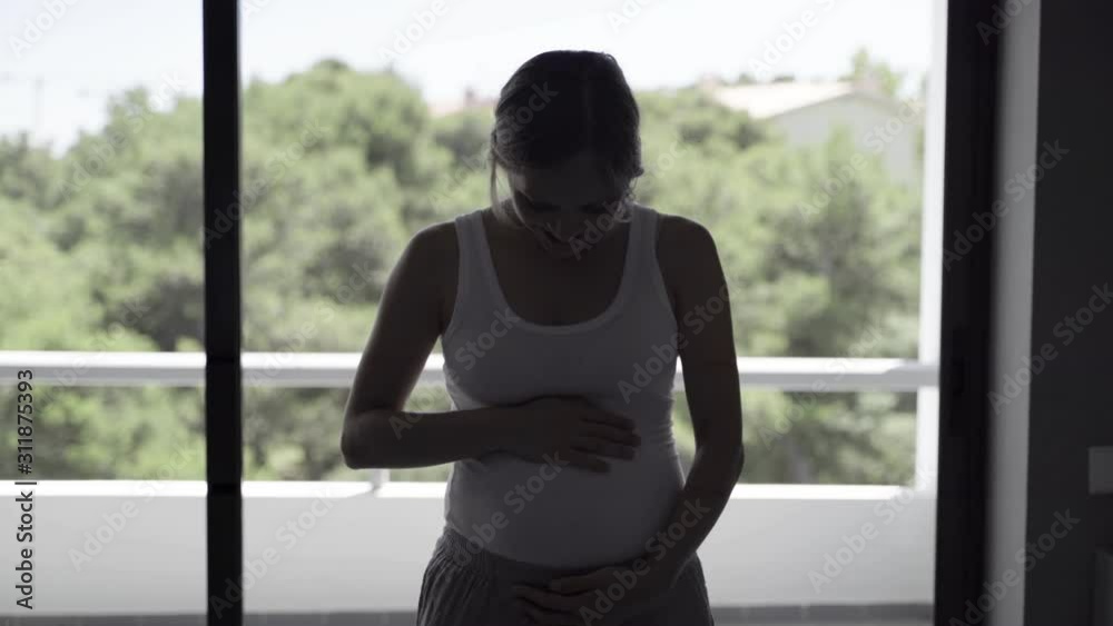 Front view of beautiful pregnant woman. Happy expectant mother standing near window. Pregnancy concept Front view of beautiful pregnant woman. Happy expectant mother standing near window. Pregnancy concept
