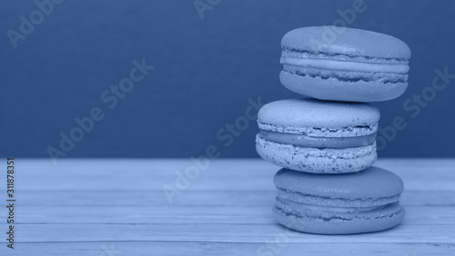 Orange and blue macaroons on a dark background  French cookies as a treat for the holiday  toned trendy classic blue color of year 2020