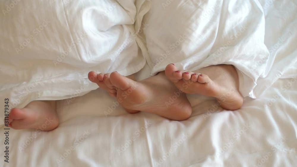 Close-up of mom's feet and a small child under a white blanket on the bed in the bedroom. Slow motion. Mother with son or daughter are played on the morning in bed. Close-up legs. Close-up of mom's feet and a small child under a white blanket on the bed in the bedroom. Slow motion. Mother with son or daughter are played on the morning in bed. Close-up legs.