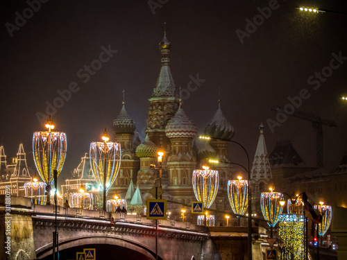 Bolshoi Moskvoretsky bridge on the background of St. Basil’s Cathedral on a snowy night. Christmas decoration in Moscow. Light illumination photo