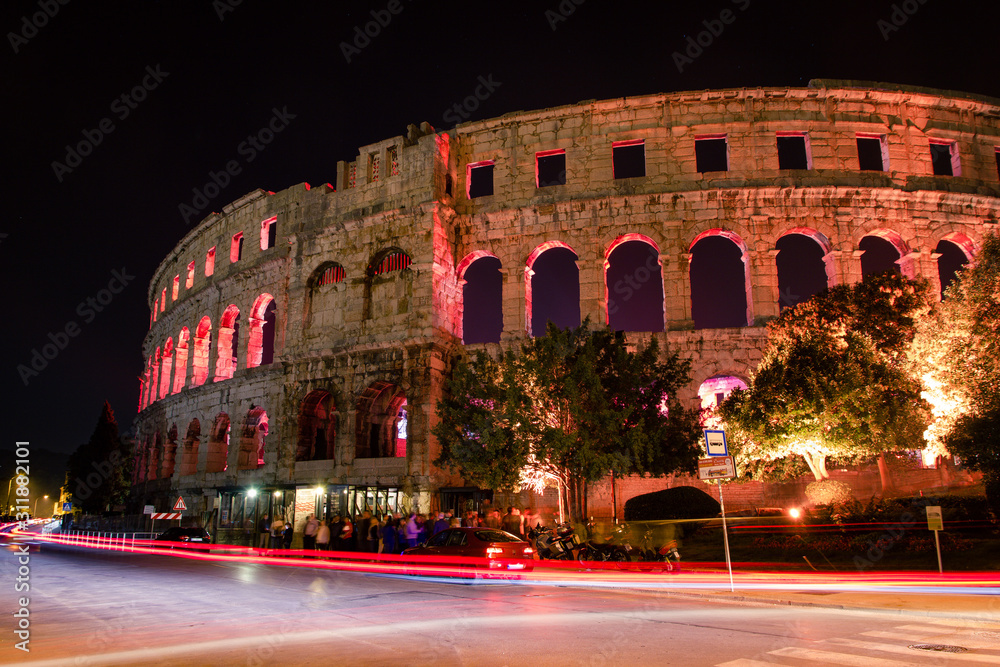 Pula, Croatia / October 9th 2018: Pula Arena by night, long exposure of cars passing by and traffic lights in front of arena