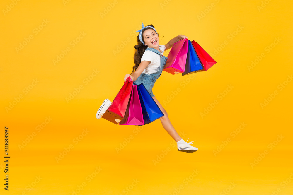 Inspiring shopping. Trends and brands. Towards discounts. Happy girl jump with shopping bags. Little child smile with paper bags. Holidays preparation and celebration. Shopping on black friday