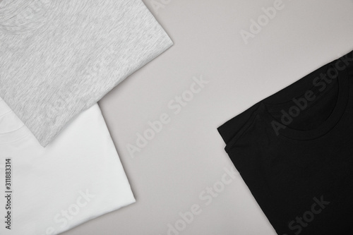 top view of blank basic black, white and grey t-shirts isolated on grey