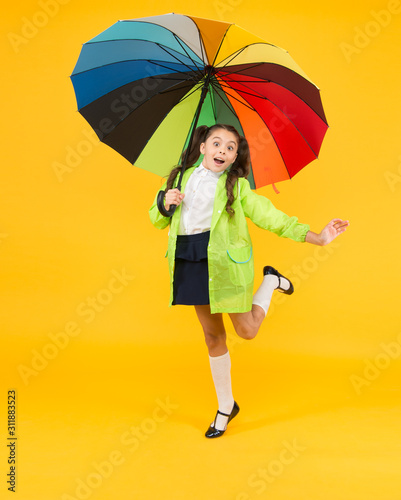 Forecast application. Positivity concept. Rainy day fun. Happy walk under umbrella. Rain concept. Kid girl happy hold colorful rainbow umbrella. Rainy weather garments. Good mood. Smiling kid