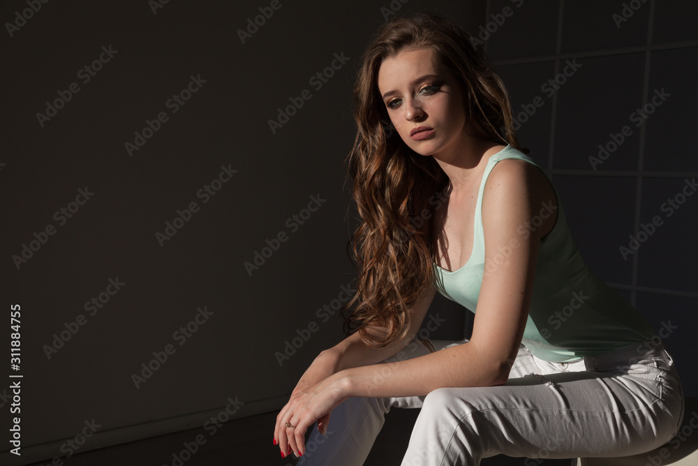 Portrait of a beautiful fashionable woman with hair curls in light clothes Portrait of a beautiful fashionable woman with hair curls in light clothes