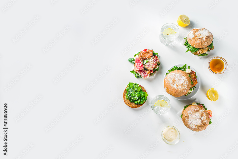Various seafood and fish burgers assortment. Homemade healthy burger with grilled prawn, salmon, tuna, sea bass, fresh herbs, mozzarella cheese and baby spinach.