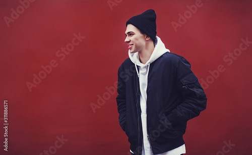 Photo fashion man in black hat dressed casual on red wall background