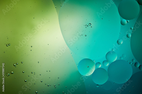 abstract background from mixed water and oil bubbles in green and turquoise color