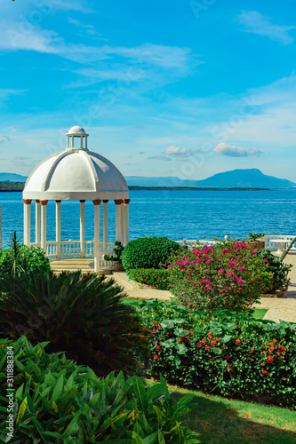 Beautiful white gazebo and tropical flower garden on Caribbean ocean background, summer mountain view , Sosua, Puerto Plata, Dominican Republic