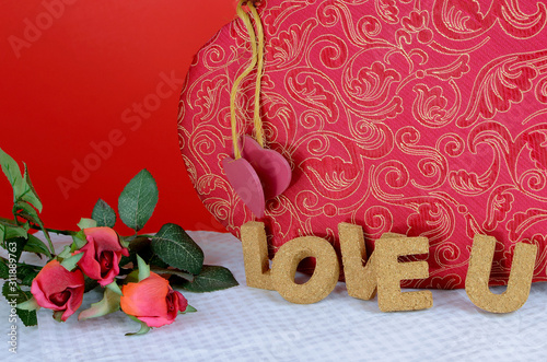 A beautiful red and gold candy box on a white table with a red background. Cork letters spell the words love u for Valentine's Day in February photo