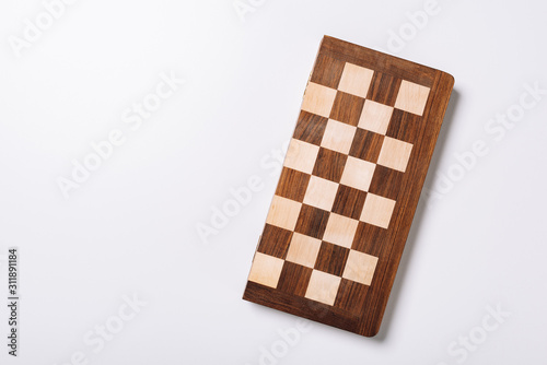 Top view of wooden checkerboard on white background with copy space