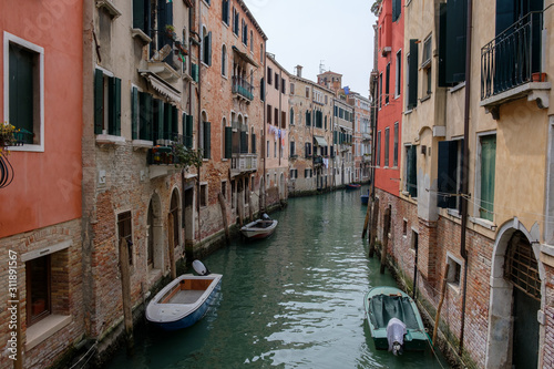 Narrow canal between residential buildings, boats on the water. Venice, Italy.