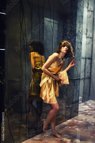 Glamorous girl in a silk robe in a dark interior of mirrors.