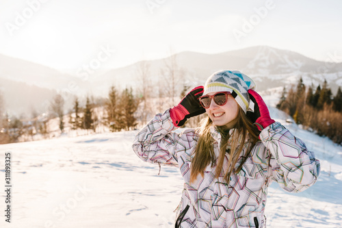 Girl enjoys the snowy winter mountains. Walk in nature. Frost season. Holidays concept. Trekking in mountains. Cold weather, snow on hills. Hiking. Mountaineer on the top in a sunny winter day.