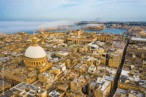 Aerial view of Valletta, dome, church. Clouds, fog on blue sky. Malta country 