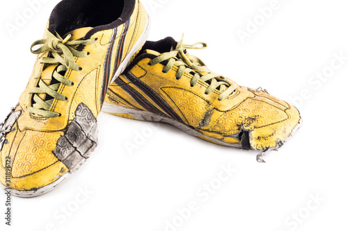 Old used  yellow worn out futsal sports shoes  on white background soccer sportware object isolated