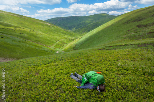 Fotografija Tired woman lying in grass at mountain