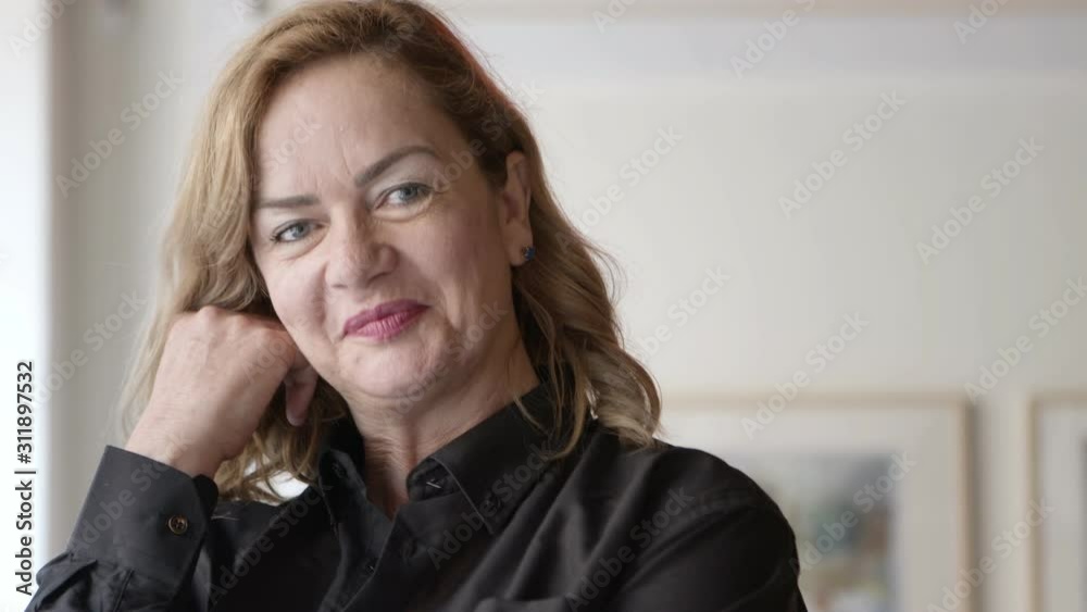 Confident businesswoman smiling at camera. Close-up portrait of beautiful middle aged businesswoman with hand on chin and smiling at camera. Business concept Confident businesswoman smiling at camera. Close-up portrait of beautiful middle aged businesswoman with hand on chin and smiling at camera. Business concept