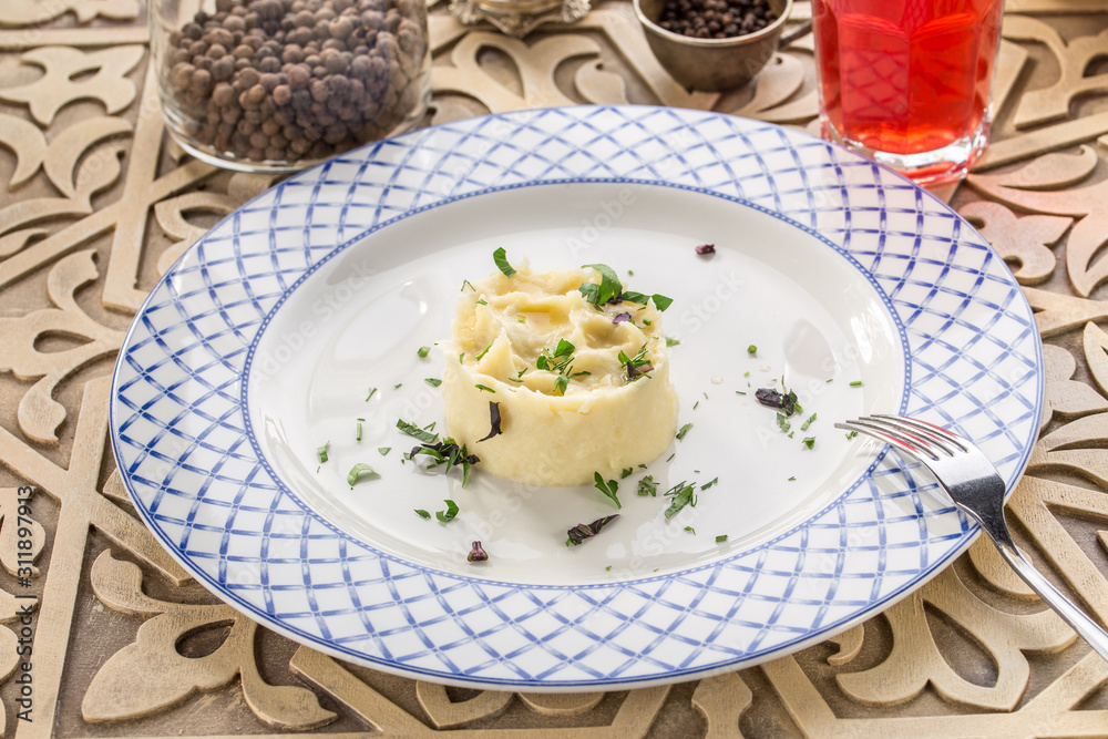 Mashed potato with dill and glass of red drink on orienral wooden table