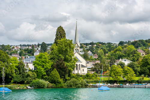 Beautiful buildings and a gothic church on the hills and the lakeshore of Lake of Zurich, Switzerland.